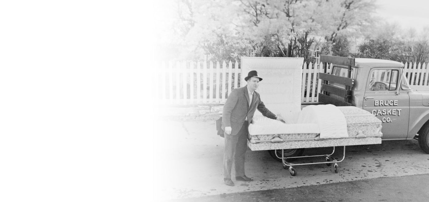 Vintage Black and White Photo of Bruce Elder next to the Bruce Casket Company Truck showing a cloth covered casket
