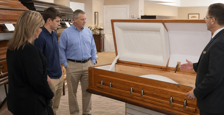 A funeral professional showing a family how a ceremonial rental casket works while in the showroom.