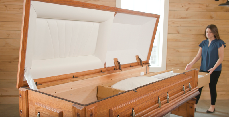 A woman pushing a rental casket insert into an open wood ceremonial casket